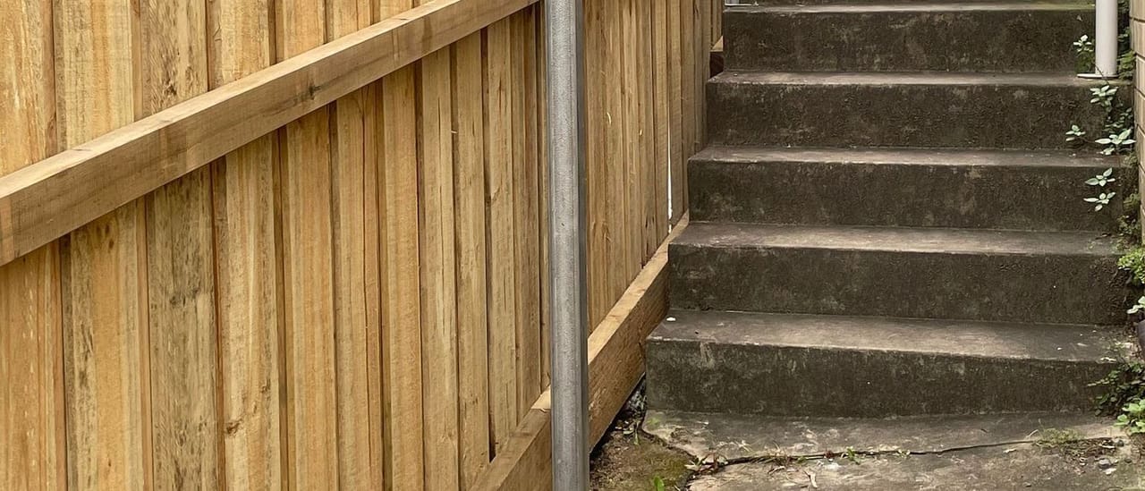 Treated pine timber fence built alongside concrete stairs on a steeply sloping Sydney site