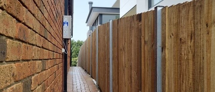 Treated pine timber fence built along a narrow brick paved laneway at a Sydney property