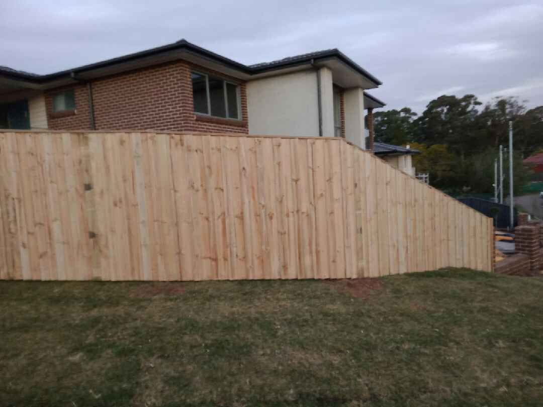 Treated pine timber fence stepped down a sloping boundary behind a brick home in Sydney