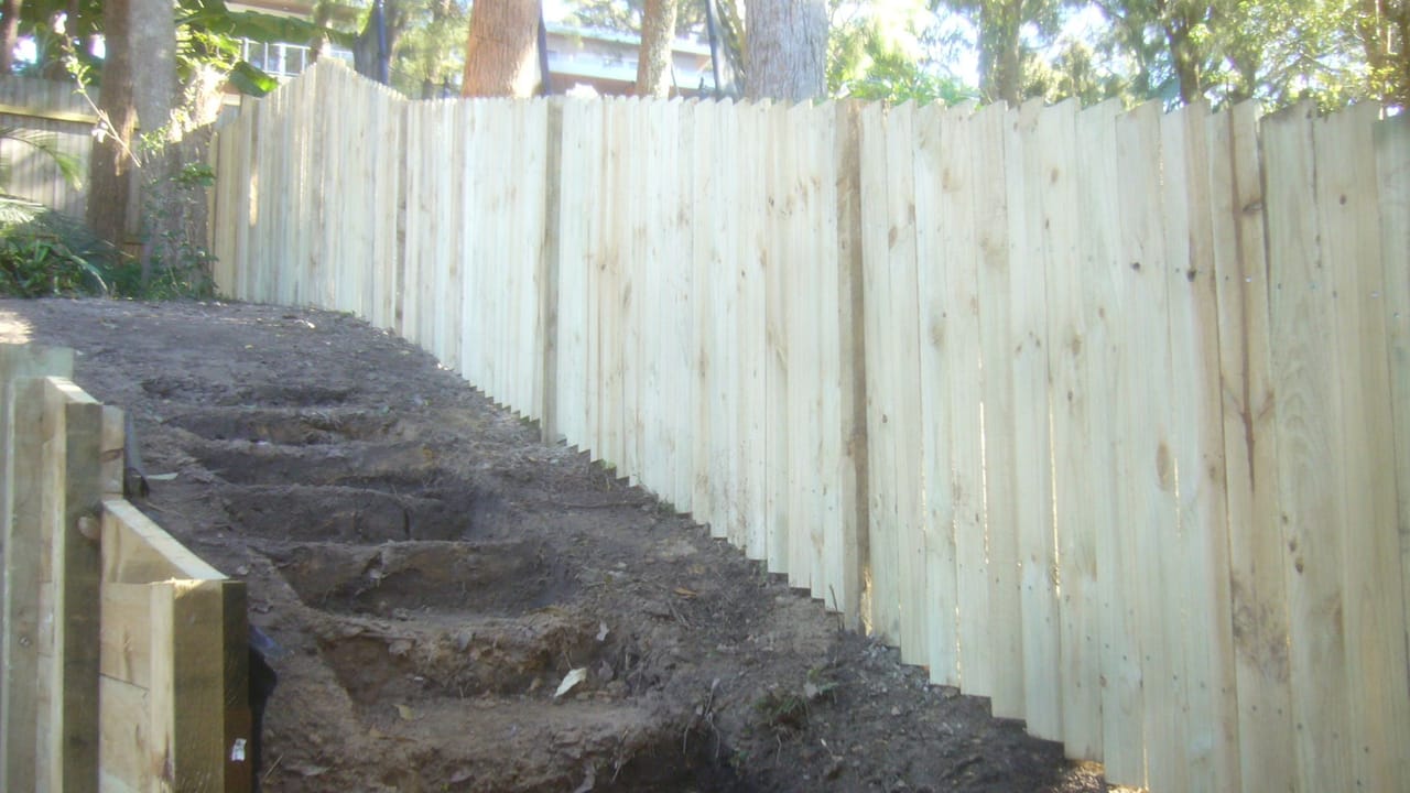 Treated pine timber fence stepped down sloping ground alongside excavated steps in Windsor, Sydney