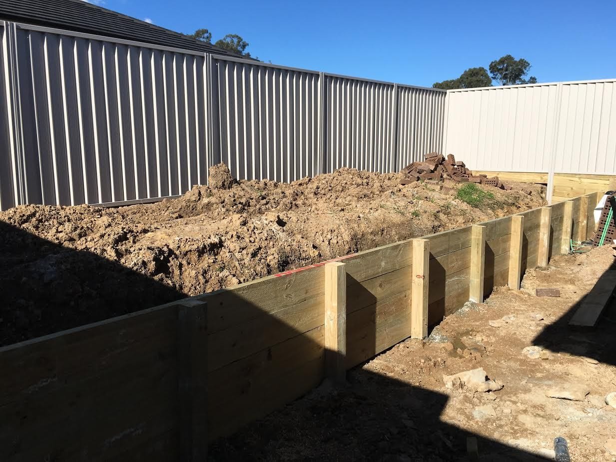 Treated pine timber sleeper retaining wall built along a cut batter at a Sydney property