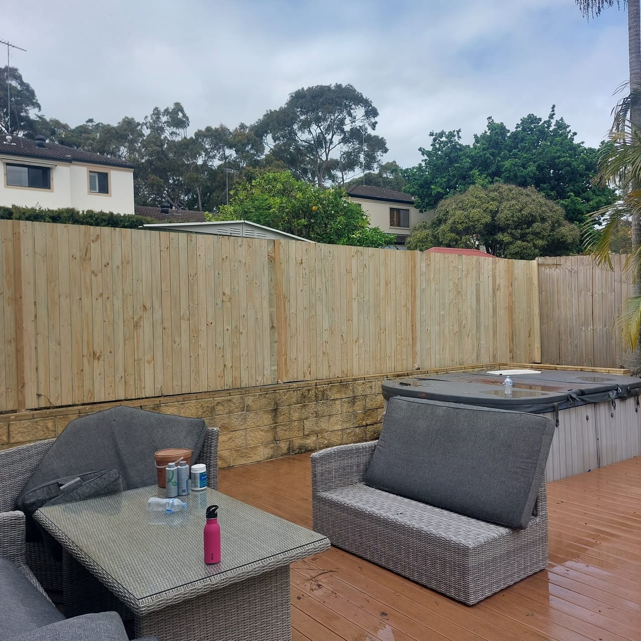 Treated pine timber fence enclosing a paved outdoor living area with lounge seating at a Sydney home