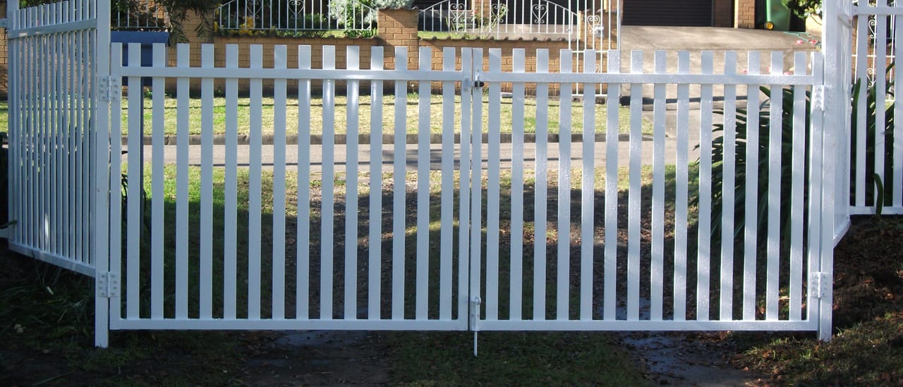 White painted timber picket double gates installed at the driveway entrance of a Sydney home